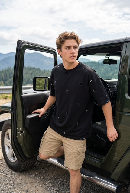 Man getting out of jeep wearing The Cross dropped shoulder max weight tee shirt in black-hand-illustrated cross pattern-Fox and Form. Men's Signature Collection. 