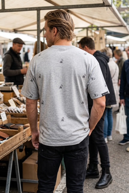 Back view of The Fox sports grey dropped shoulder max weight tee shirt with hand-etched illustrated fox pattern design, worn at an outdoor market. Fox and Form Men's Signature Collection. 