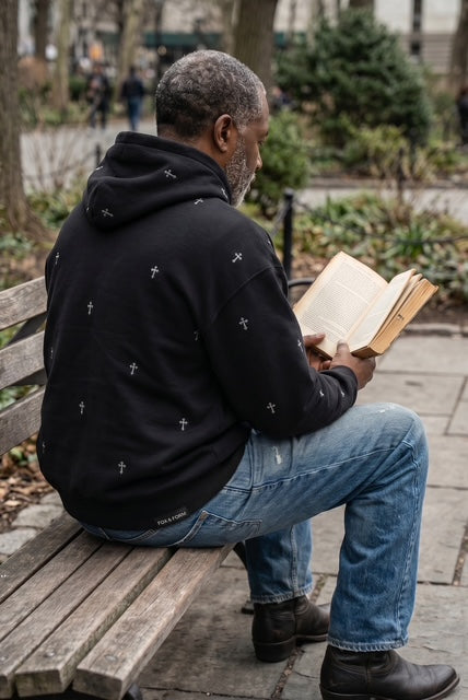 Man sitting reading outdoors wearing The Cross-max weight sweatshirt in black with hand illustrated cross pattern design Fox and Form. Fox and Form Men's Signature Collection 